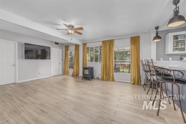 4610 Power Rd, Ontario, OR 97914 - living room featuring a wood stove, baseboards, a ceiling fan, and light wood-type flooring