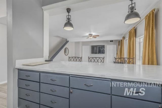 4610 Power Rd, Ontario, OR 97914 - kitchen with ceiling fan, gray cabinets, hanging light fixtures, and light stone counters