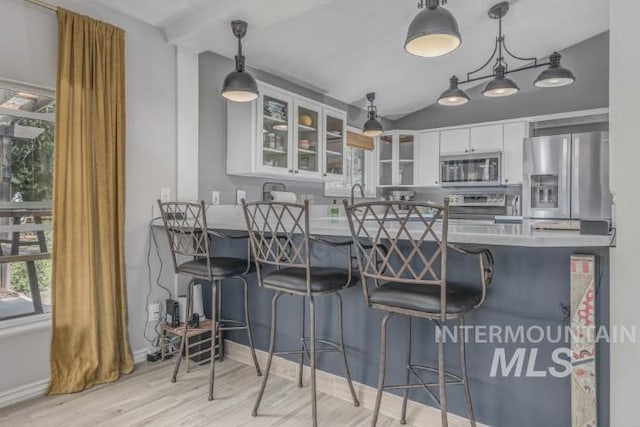4610 Power Rd, Ontario, OR 97914 - kitchen featuring stainless steel appliances, glass insert cabinets, a peninsula, wood finished floors, and white cabinetry