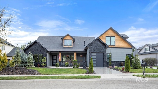 view of front of property featuring concrete driveway, stone siding, an attached garage, a front lawn, and a porch