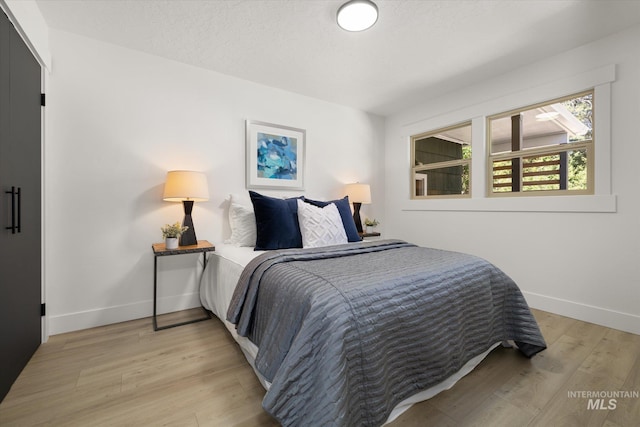 bedroom with light wood-type flooring and baseboards