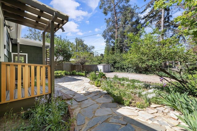 view of patio / terrace with a storage shed, an outdoor structure, fence, and a pergola