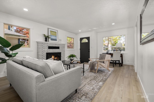 living area featuring a fireplace, baseboards, light wood-style floors, and recessed lighting