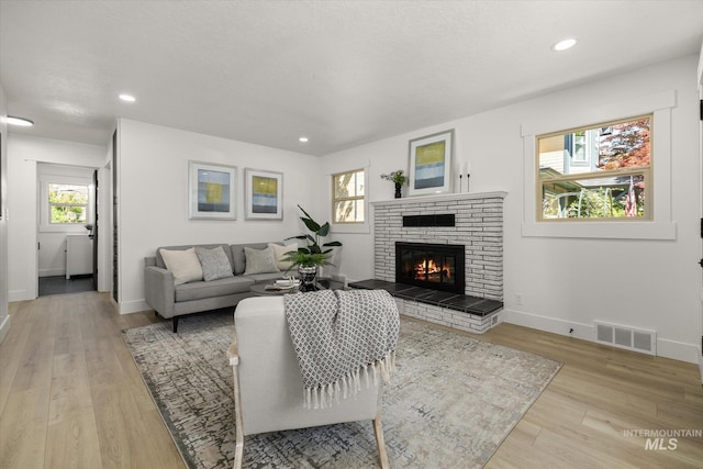 living room with a fireplace, light wood-style floors, baseboards, and recessed lighting