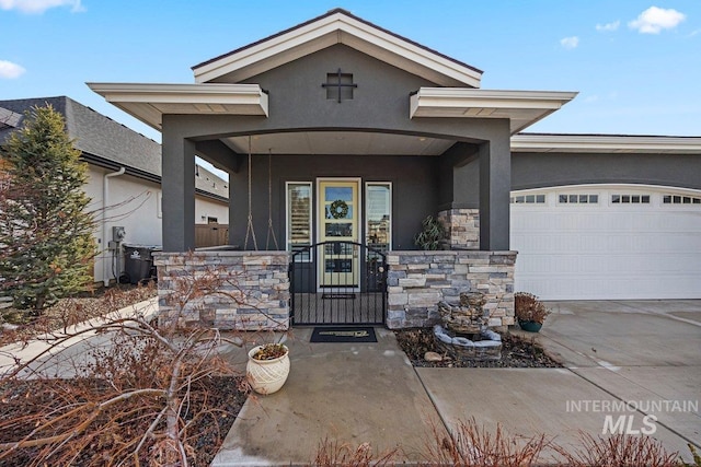 view of front of house featuring driveway, stone siding, an attached garage, covered porch, and stucco siding