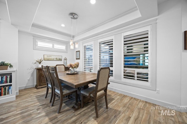 dining space featuring crown molding, wood finished floors, a raised ceiling, and baseboards