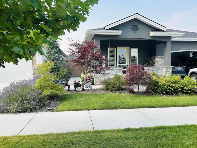 view of front of house with a garage, a front yard, stone siding, and stucco siding