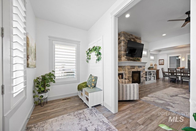 sitting room featuring baseboards, a ceiling fan, light wood-style floors, a fireplace, and recessed lighting