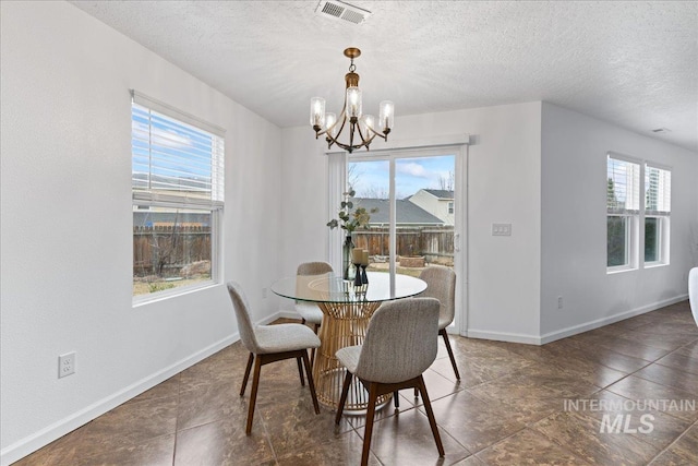 dining space with a notable chandelier, visible vents, a textured ceiling, and baseboards