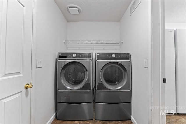 washroom with visible vents, a textured ceiling, separate washer and dryer, baseboards, and laundry area