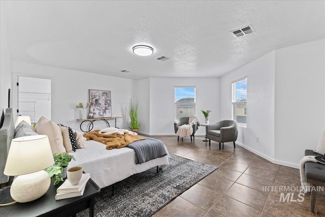 bedroom with visible vents, baseboards, and a textured ceiling