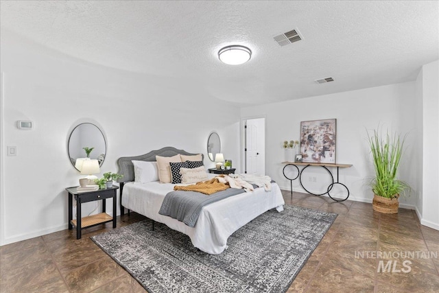 bedroom featuring visible vents, baseboards, and a textured ceiling