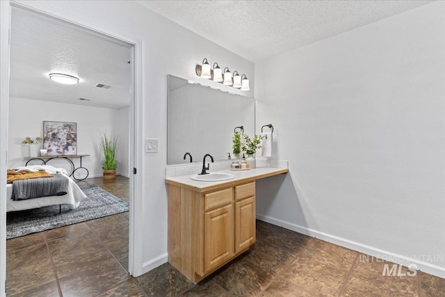 bathroom with vanity, visible vents, baseboards, and a textured ceiling