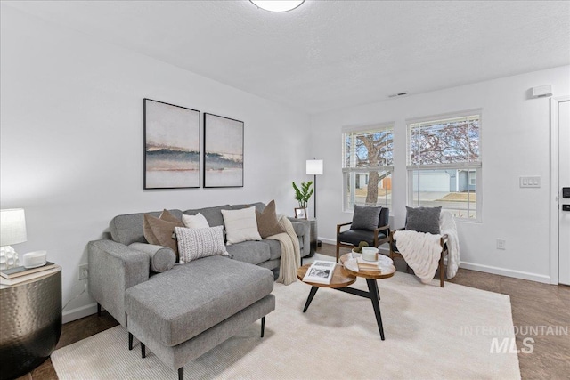 living room with visible vents, a textured ceiling, baseboards, and wood finished floors