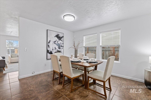 dining area featuring baseboards and a textured ceiling