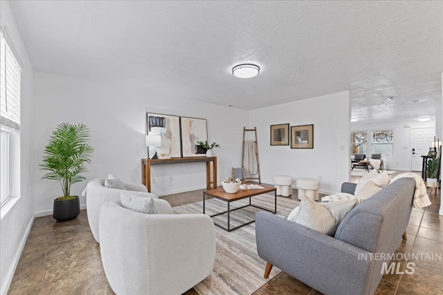 living room featuring baseboards, a wealth of natural light, and a textured ceiling