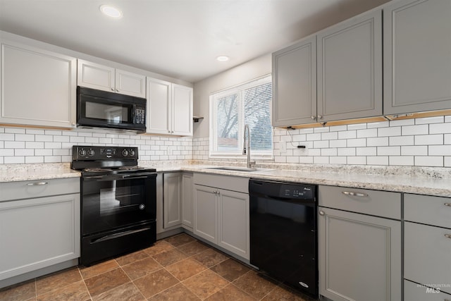 kitchen with tasteful backsplash, gray cabinets, sink, and black appliances