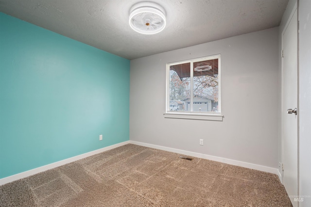 unfurnished room with carpet and a textured ceiling