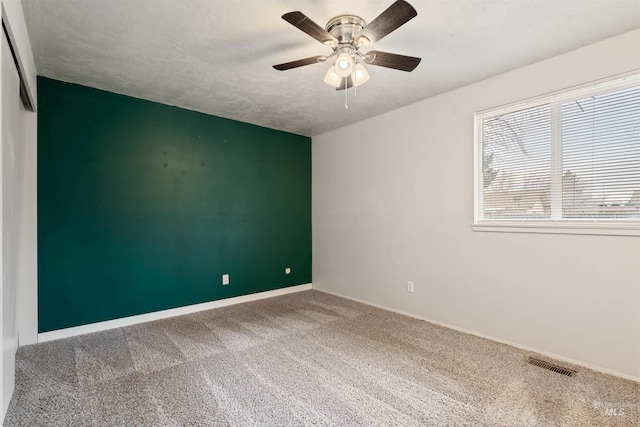 empty room with ceiling fan, carpet floors, and a textured ceiling