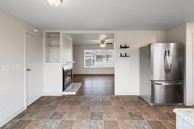 kitchen with stainless steel fridge, a large fireplace, dark hardwood / wood-style flooring, and ceiling fan