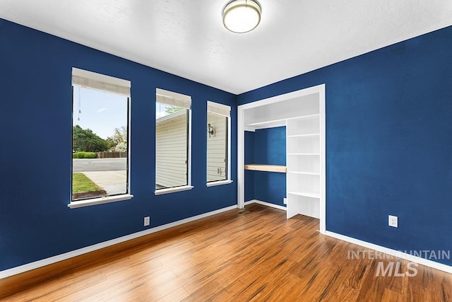 spare room featuring baseboards and wood finished floors