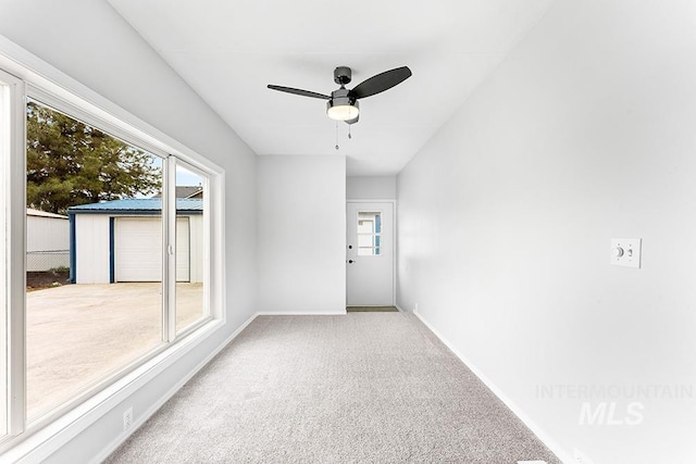 empty room featuring carpet floors, a ceiling fan, baseboards, and a wealth of natural light