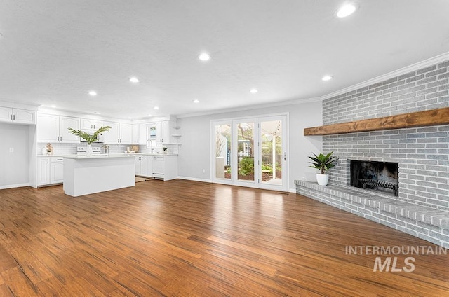 unfurnished living room featuring recessed lighting, ornamental molding, a sink, and wood finished floors