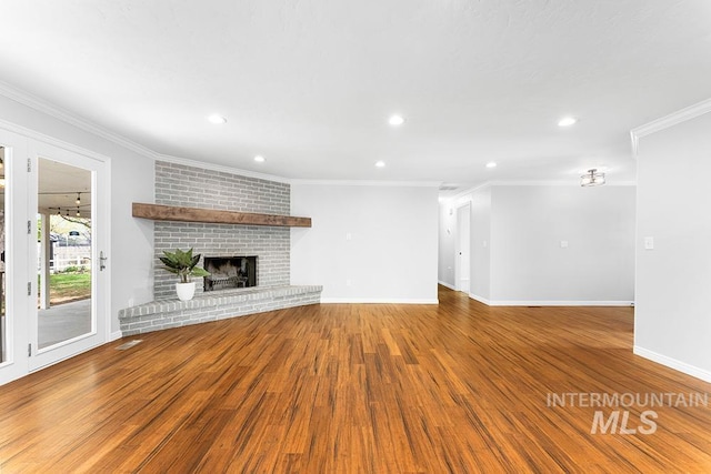 unfurnished living room with crown molding, wood finished floors, a fireplace, baseboards, and recessed lighting