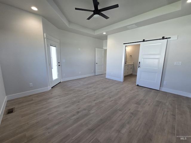 531 Full Moon Way, Twin Falls, ID 83301 - unfurnished bedroom featuring a barn door, a raised ceiling, recessed lighting, wood finished floors, and ensuite bathroom