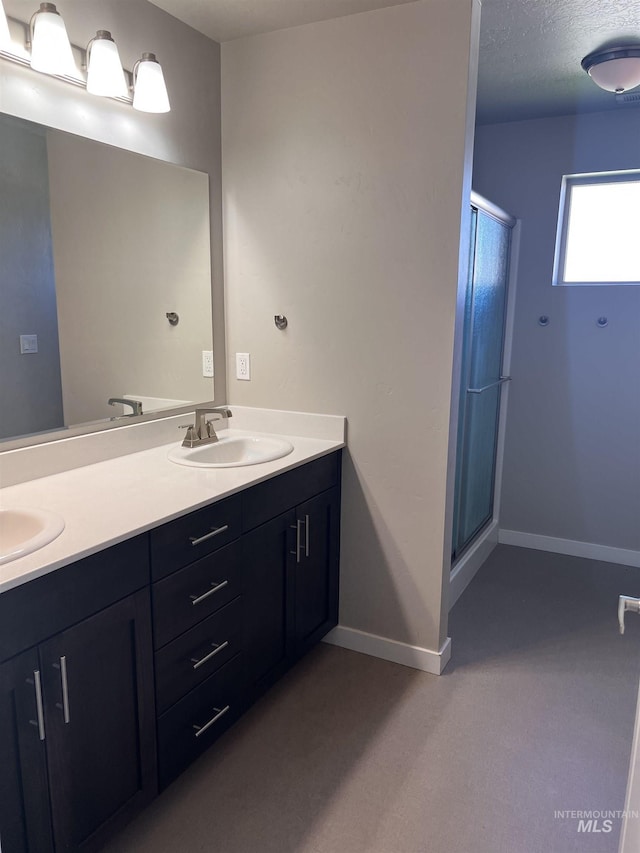 bathroom with vanity, a shower with door, and a textured ceiling