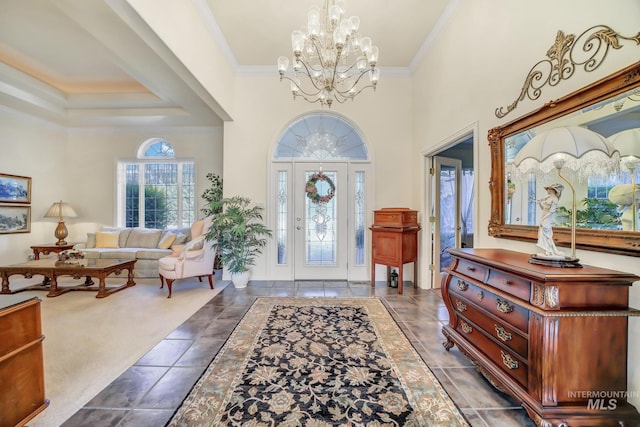 carpeted foyer with crown molding, a towering ceiling, and an inviting chandelier