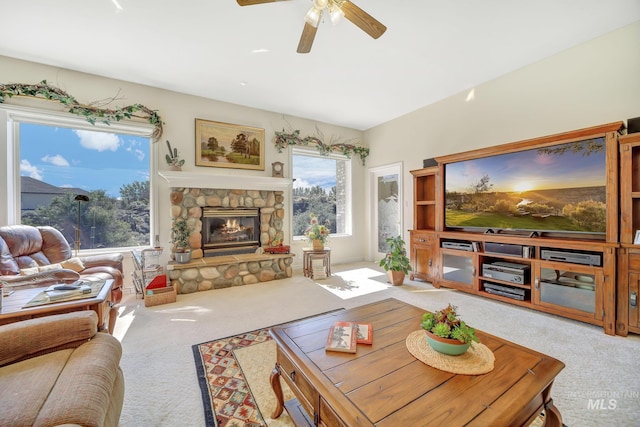 living room with light colored carpet, a stone fireplace, and ceiling fan