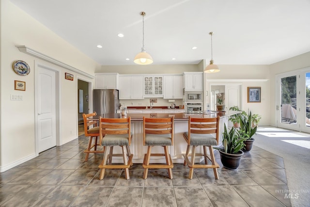 kitchen with a kitchen island, decorative light fixtures, a breakfast bar, white cabinets, and appliances with stainless steel finishes