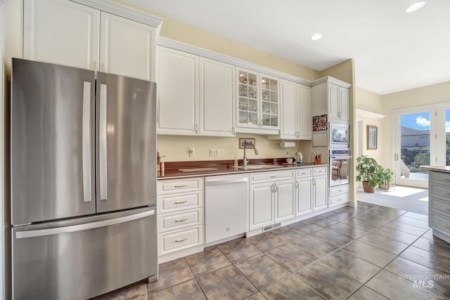 kitchen with white cabinets, appliances with stainless steel finishes, dark tile patterned floors, and sink