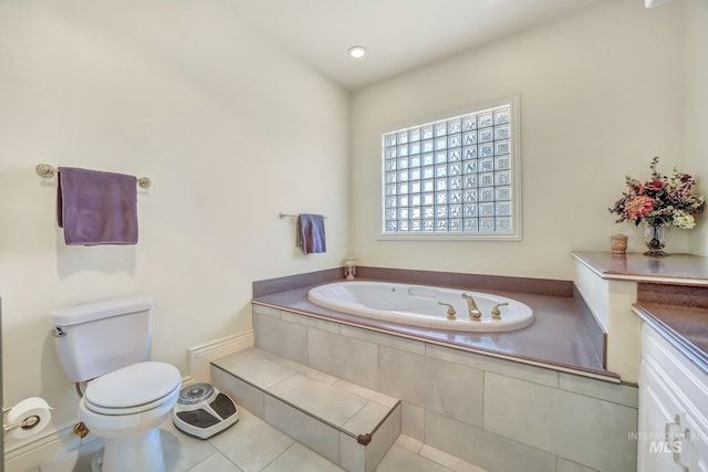 bathroom with tile patterned flooring, a relaxing tiled tub, toilet, and vanity