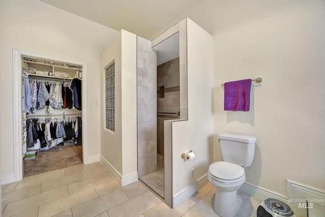 bathroom with tile patterned floors, toilet, and tiled shower