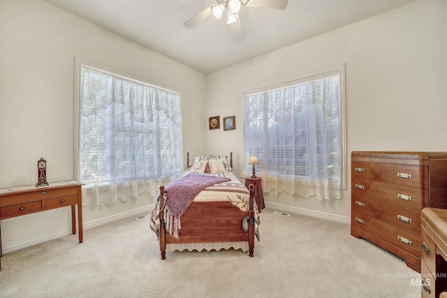 bedroom featuring ceiling fan, light colored carpet, and multiple windows