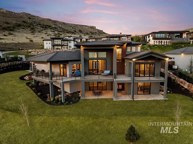 1519 S Galaxy Way, Boise, ID 83712 - back of property at dusk featuring a patio area, a balcony, a yard, and a mountain view