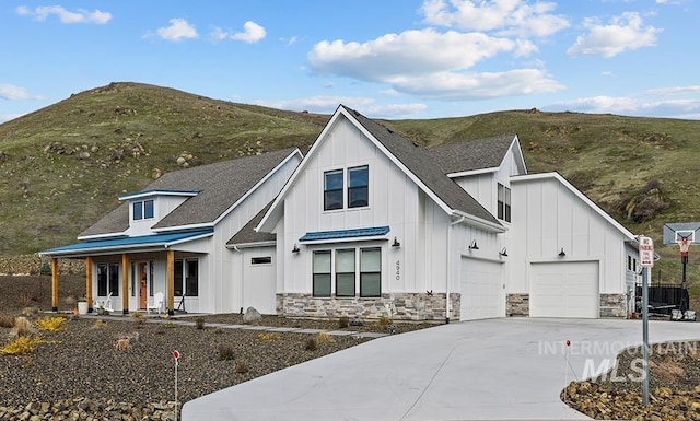 modern farmhouse with a garage, a mountain view, and covered porch