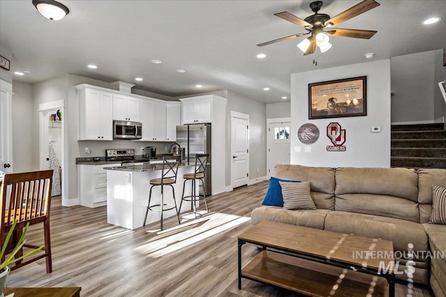 living room with ceiling fan, light wood-type flooring, and sink