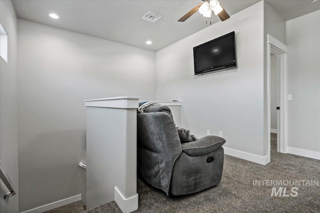 living area with ceiling fan and dark colored carpet