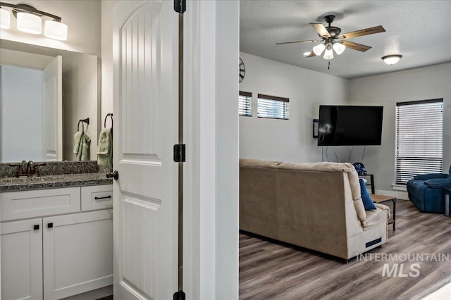 living room featuring a textured ceiling, light hardwood / wood-style floors, ceiling fan, and sink