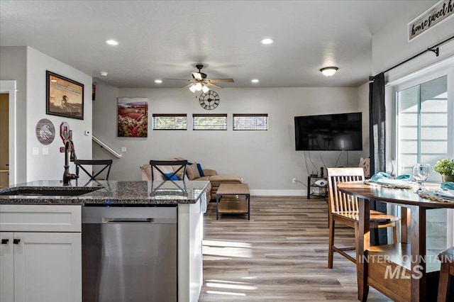 kitchen with dark stone counters, sink, stainless steel dishwasher, ceiling fan, and white cabinetry