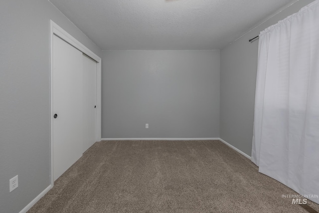 interior space featuring carpet floors, a textured ceiling, baseboards, and a closet