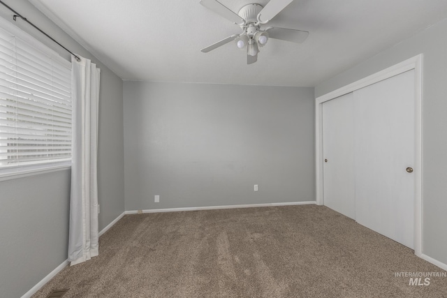unfurnished bedroom with carpet floors, baseboards, ceiling fan, and a closet