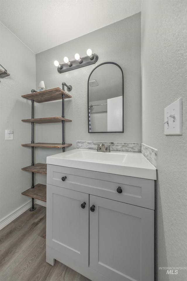 bathroom with baseboards, wood finished floors, and vanity
