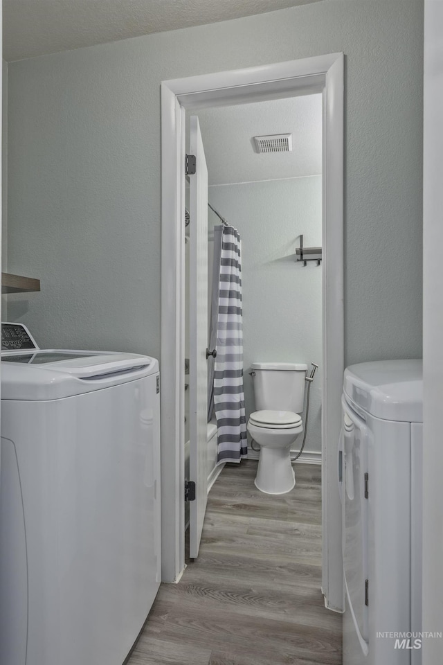 full bathroom featuring visible vents, washer and clothes dryer, wood finished floors, and toilet
