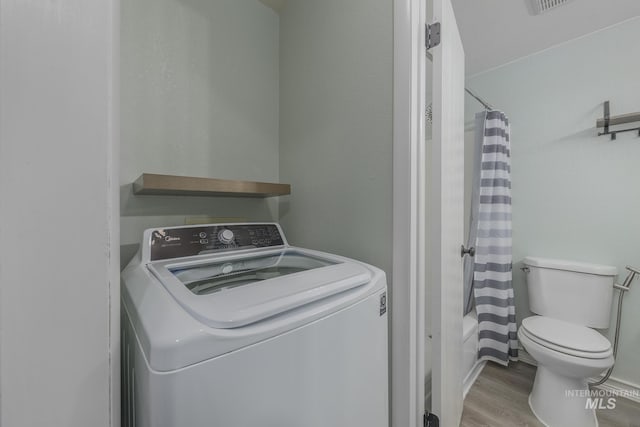 laundry room with laundry area, washer / dryer, and wood finished floors