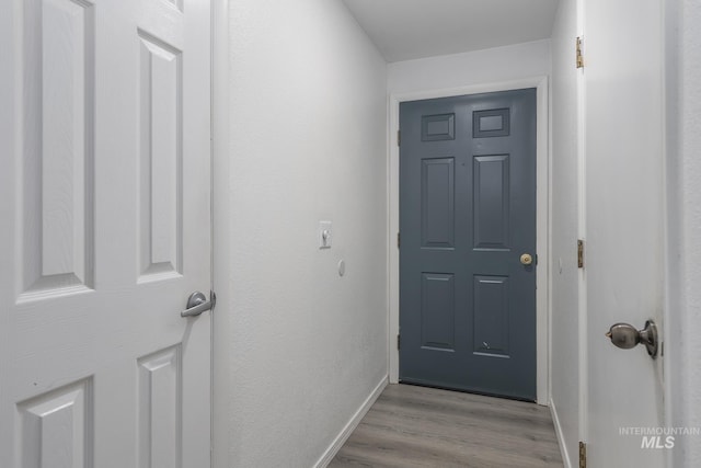 doorway with baseboards and wood finished floors