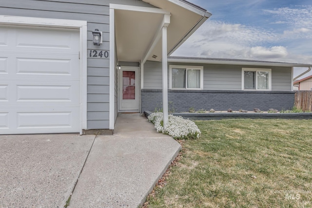 view of exterior entry featuring a yard and brick siding